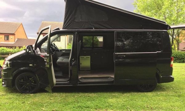 side profile of a black campervan with portfolio roof